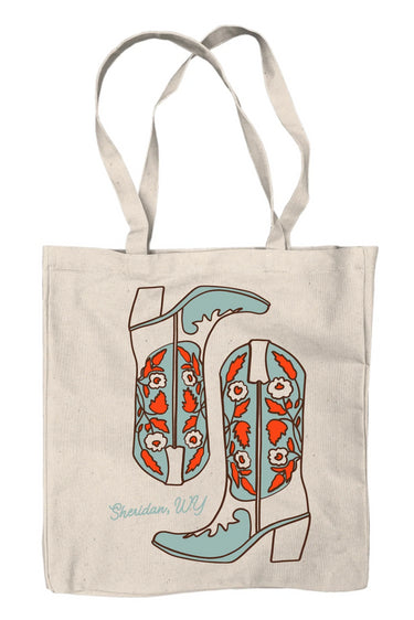A beige canvas tote bag with a graphic print of boots in shades of red and blue, and the text ' Sheridan, WY'.